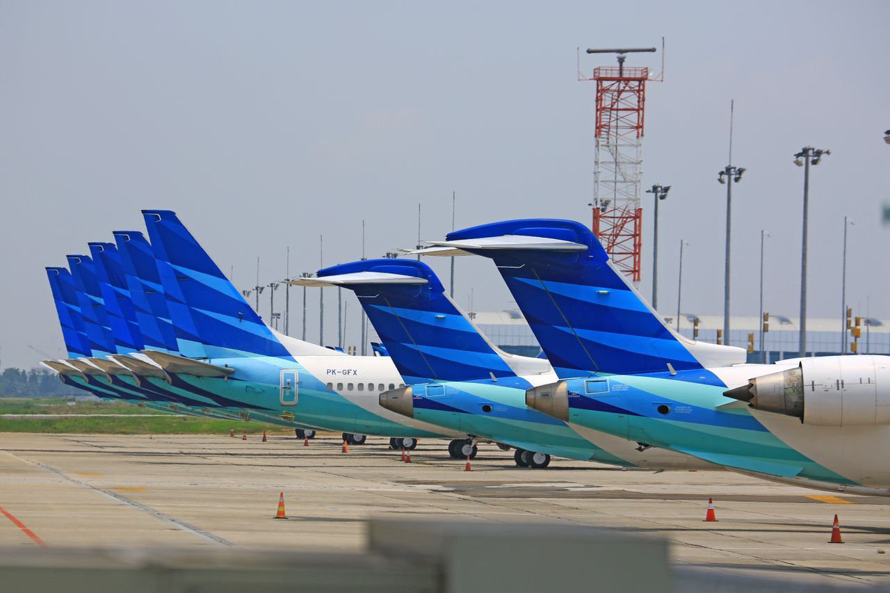 Line of Garuda Indonesia airplanes parked at an airport, showcasing aviation industry infrastructure.